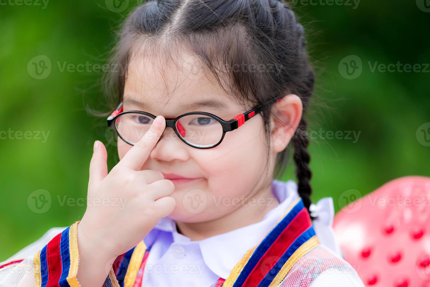 foto na cabeça de crianças fofas usam óculos devido à miopia ou leve astigmatismo. crianças em idade escolar usam o dedo indicador para empurrar os óculos para ajustá-los ao nível dos olhos ou para apertá-los. menina criança tem 6 anos.