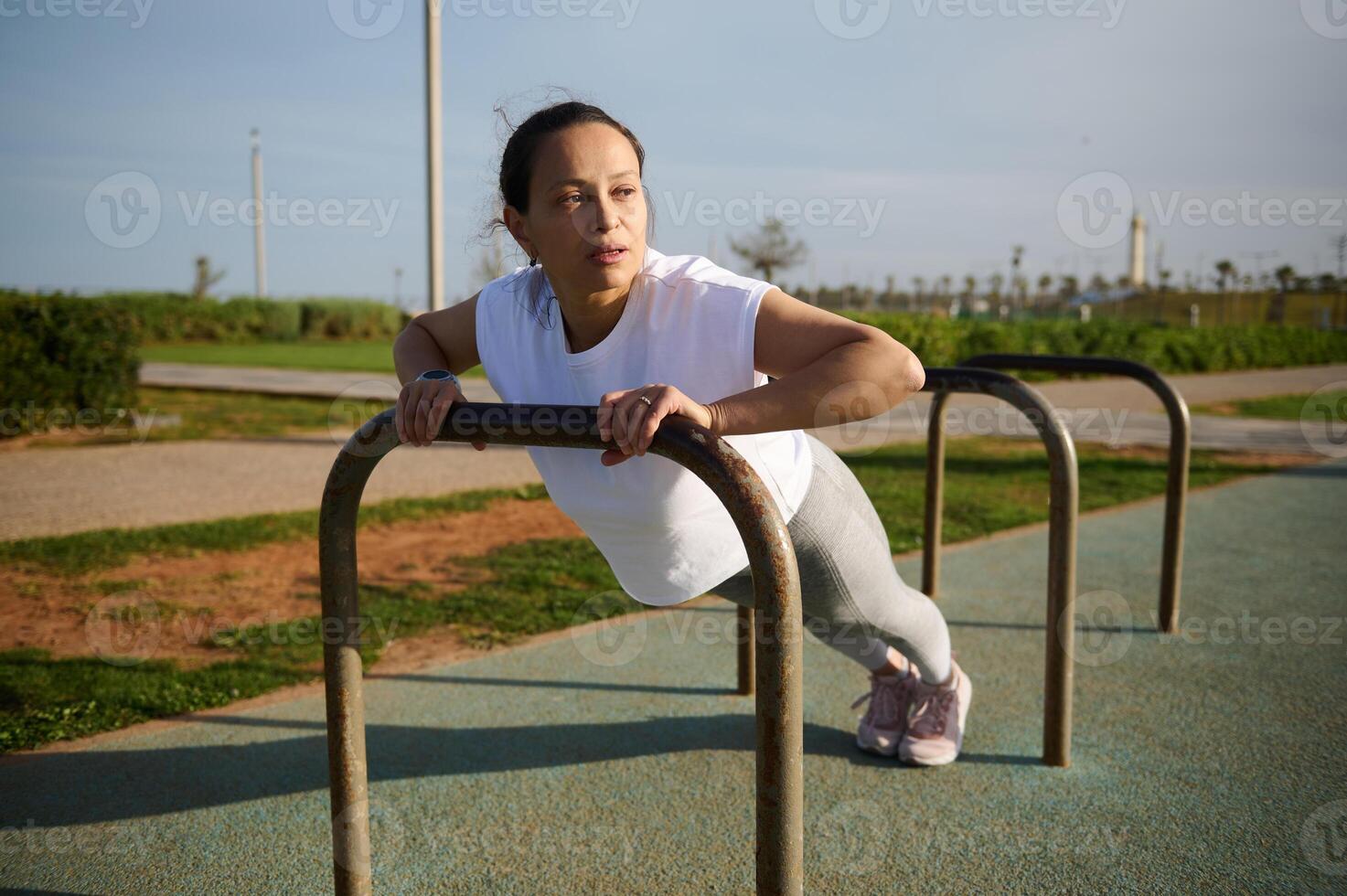 jovem mulher é acionado dentro fitness, alongamento em Esportes campo dentro cidade. ginástica mulher trabalhando Fora fazendo flexões dentro parque foto