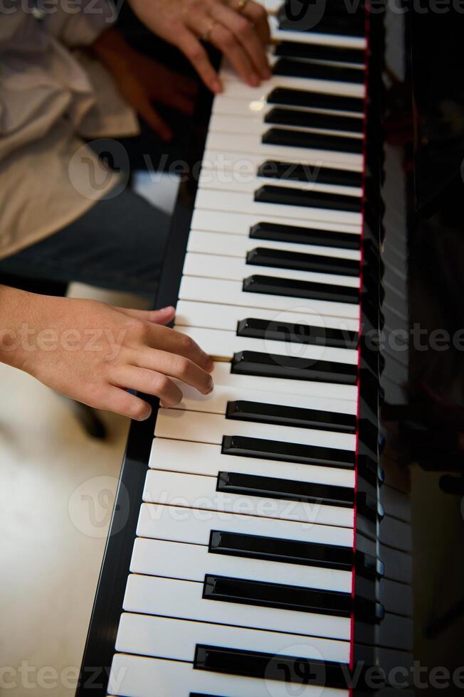 músico Garoto jogando grande piano durante música lição, realizando clássico melodia, criando e sentindo-me a ritmo do sons enquanto colocando dedos em branco e Preto piano chaves. fechar-se topo visualizar. foto