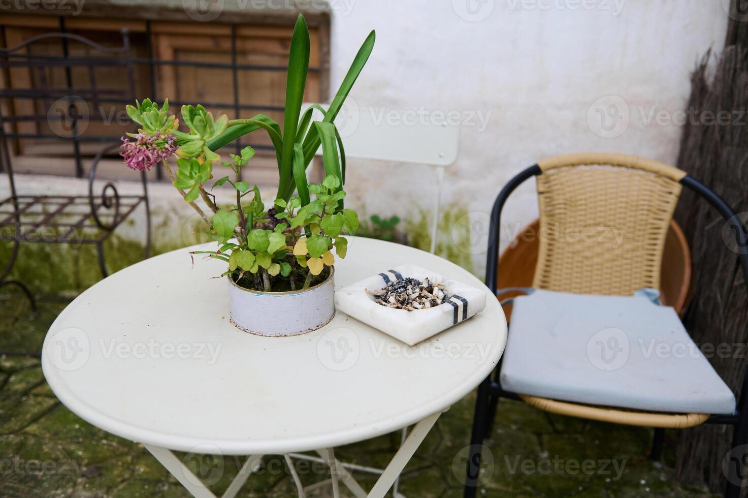 ainda vida com mármore cinzeiro com cigarro butts em mesa com cadeira dentro jardim. a conceito do pulmão Câncer doenças foto