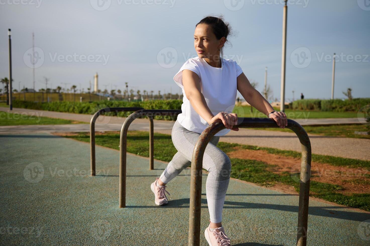 cheio comprimento retrato do fêmea atleta exercício com barra em a urbano quadra esportiva. foto