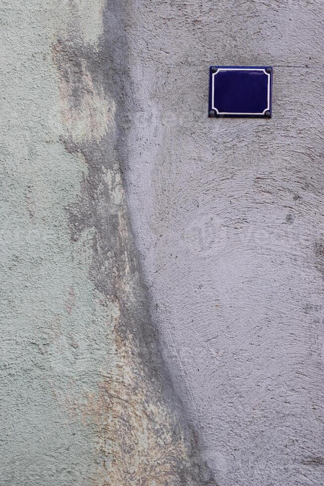cinzento esverdeado velho gasto rachado cimento parede com a clássico Projeto casa esvaziar número placa. lindo Antiguidade casa concreto parede textura. frente visualizar. cópia de espaço. foto