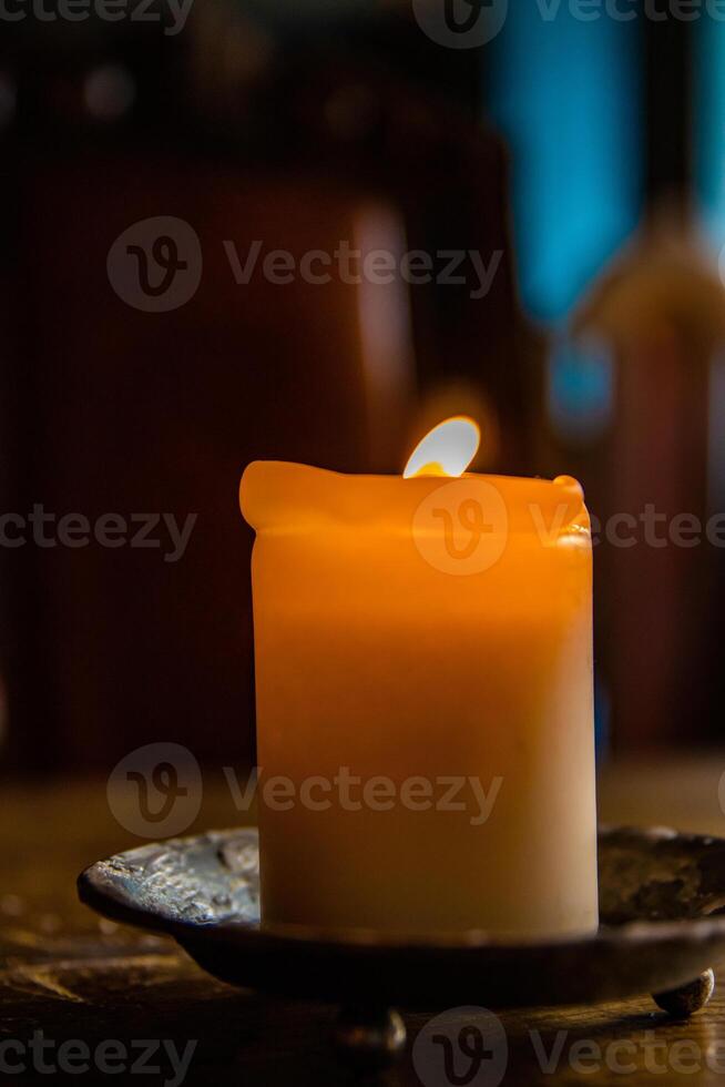 aceso vela em a de madeira mesa. queimando vela dentro a candelabro. queimando claro. quente fogo. acolhedor atmosfera. seletivo foco. luz de fundo a partir de a janela. foto