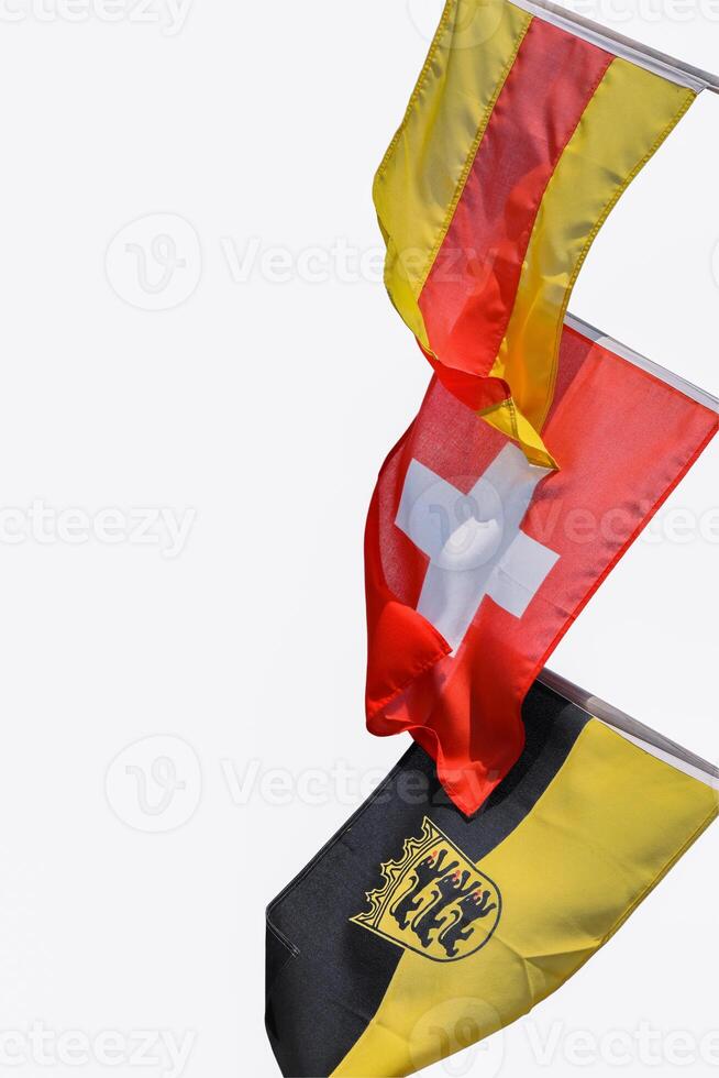três bandeiras em a mastros de bandeira acenando dentro a vento. bandeiras do Baden, Suíça, bandeira Baden-Wuerttemberg com a emblema. suíço bandeira dentro a meio. cópia de espaço. isolado em branco fundo. recorte caminho foto