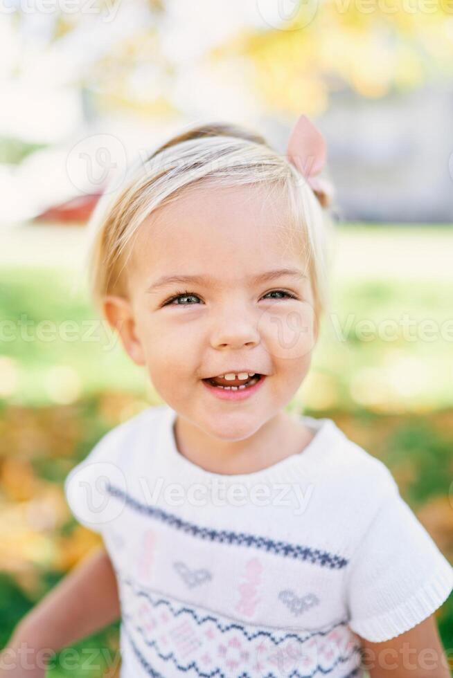 pequeno sorridente menina dentro uma Rosa arco de cabelo com uma arco. retrato foto