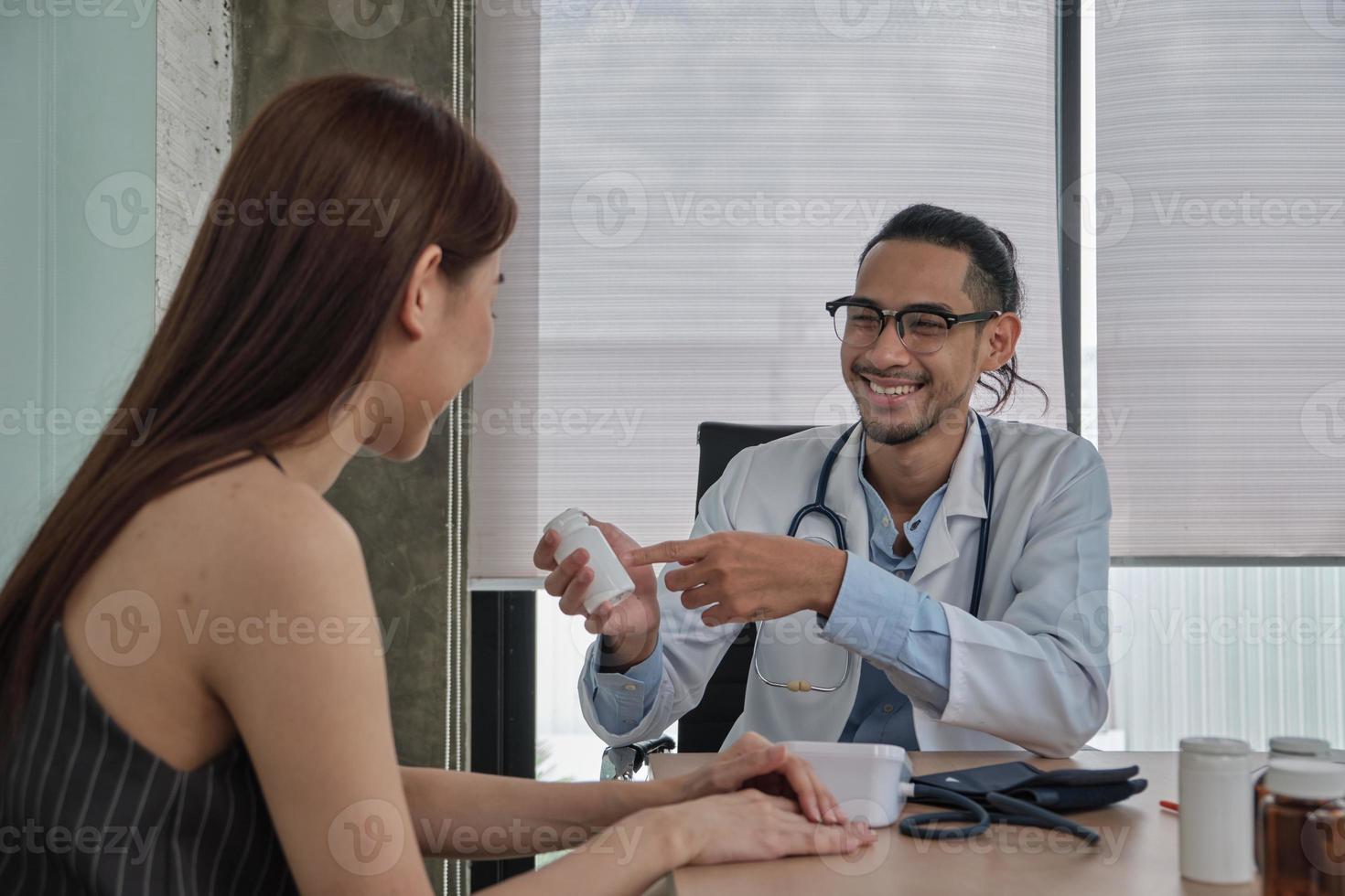 tratamento médico e check-up, jovem médico fala com um sorriso e examina uma paciente de etnia asiática durante uma consulta de saúde, aconselhamento em uma clínica de hospital. foto