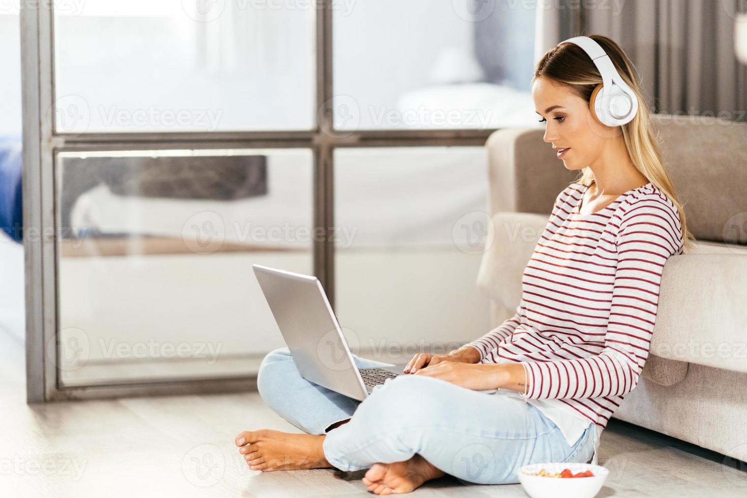 jovem com fones de ouvido e laptop no sofá foto