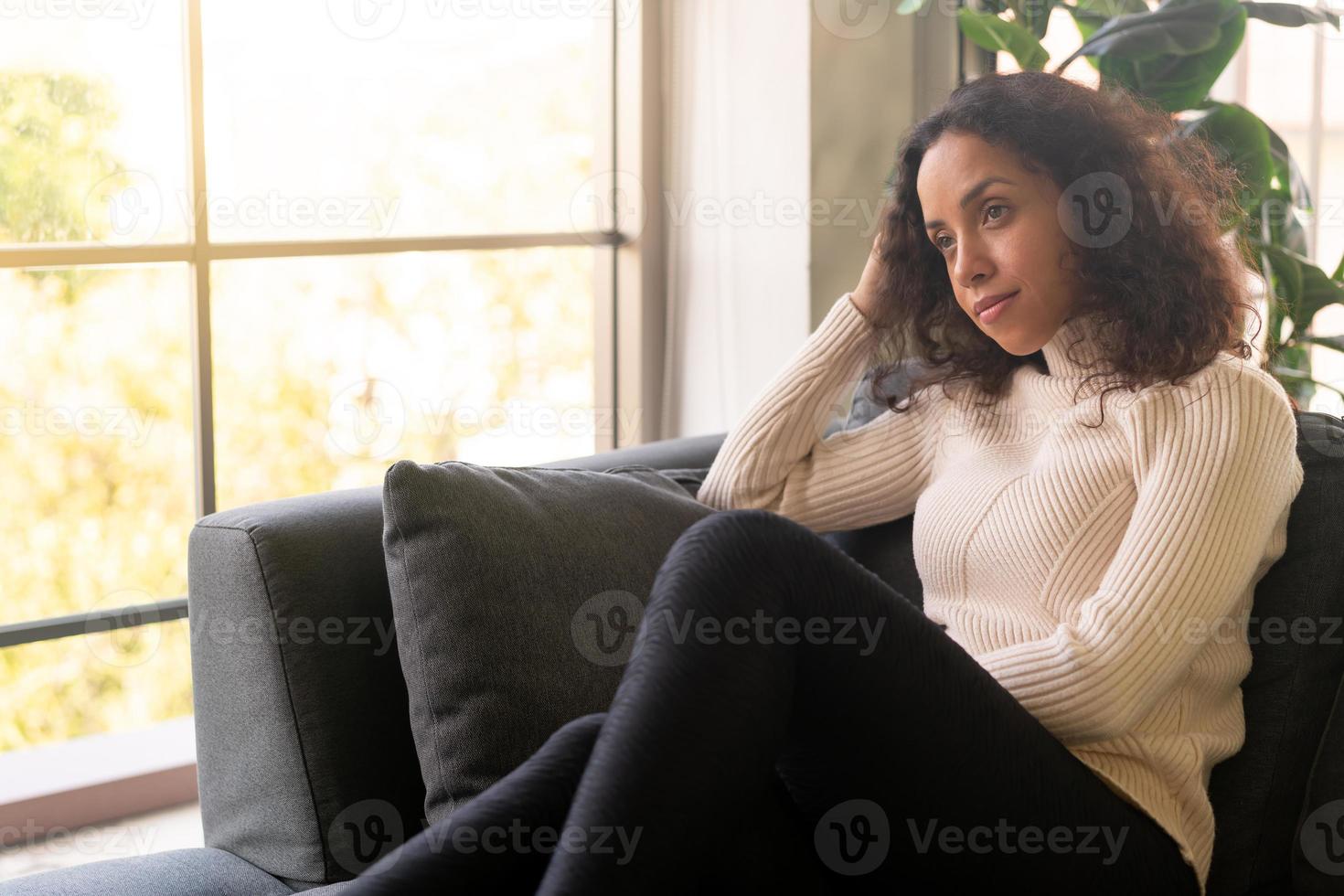 mulher latina sentada no sofá com um sentimento de solidão foto