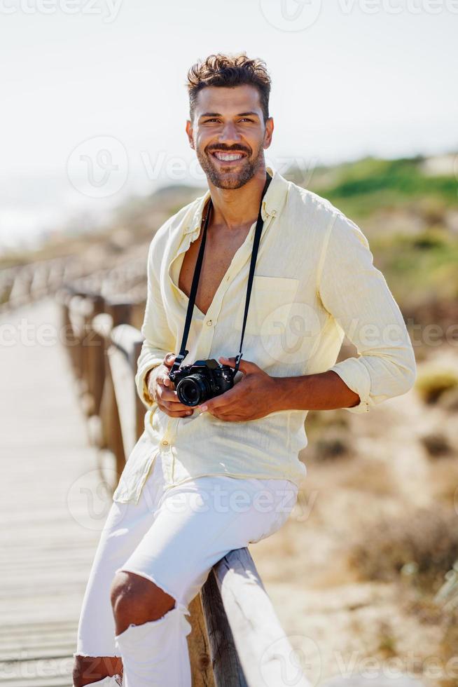 homem sorridente fotografando em uma área costeira. foto