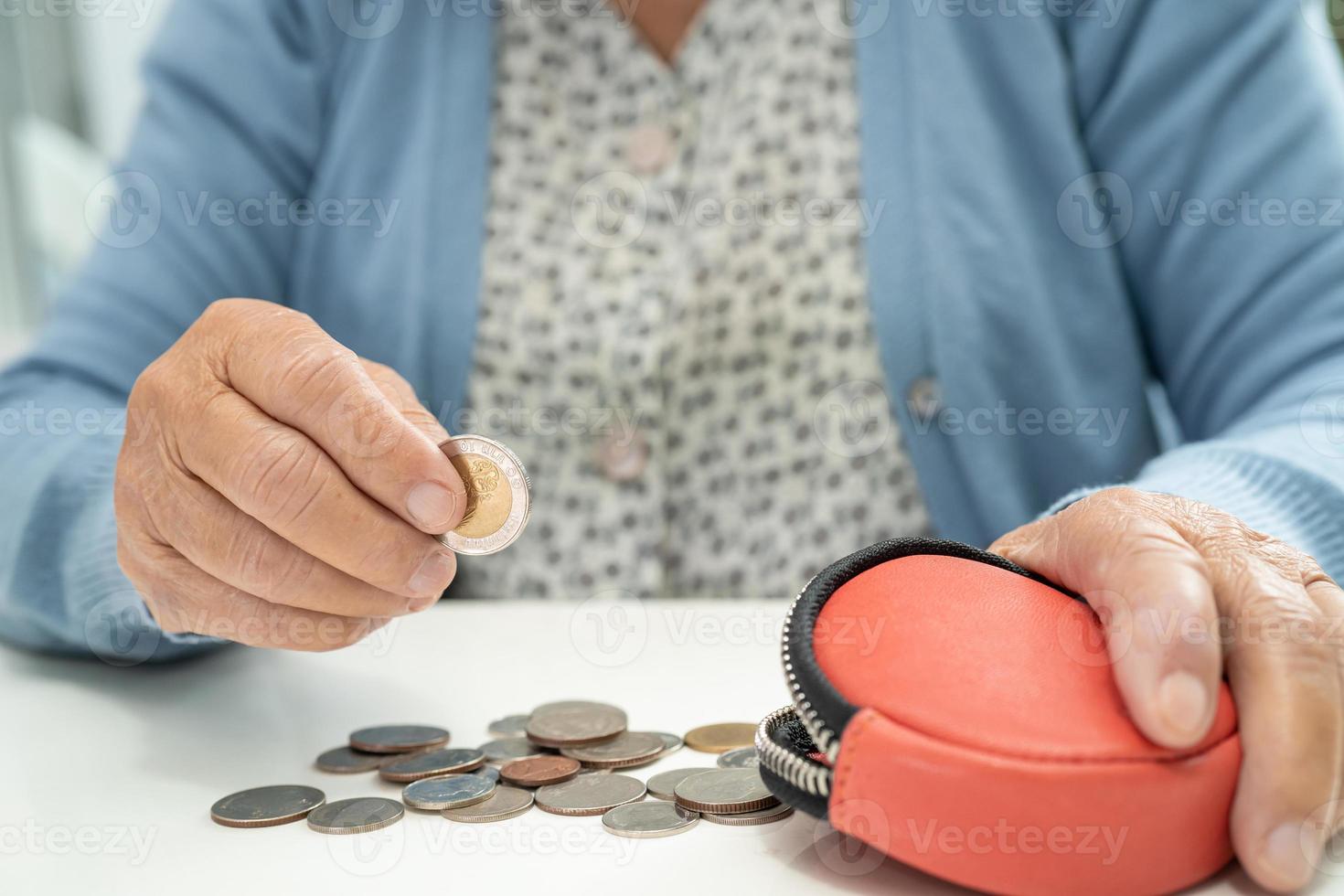 mulher idosa sênior ou idosa asiática segurando contando dinheiro moedas na bolsa. pobreza, problema de poupança na aposentadoria. foto