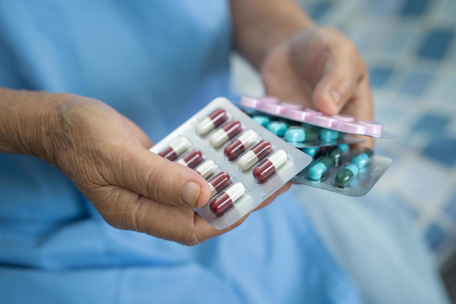 paciente asiático sênior ou idosa senhora segurando comprimidos da cápsula de antibióticos em embalagem blister para paciente de infecção de tratamento no hospital, conceito de farmácia farmácia. foto