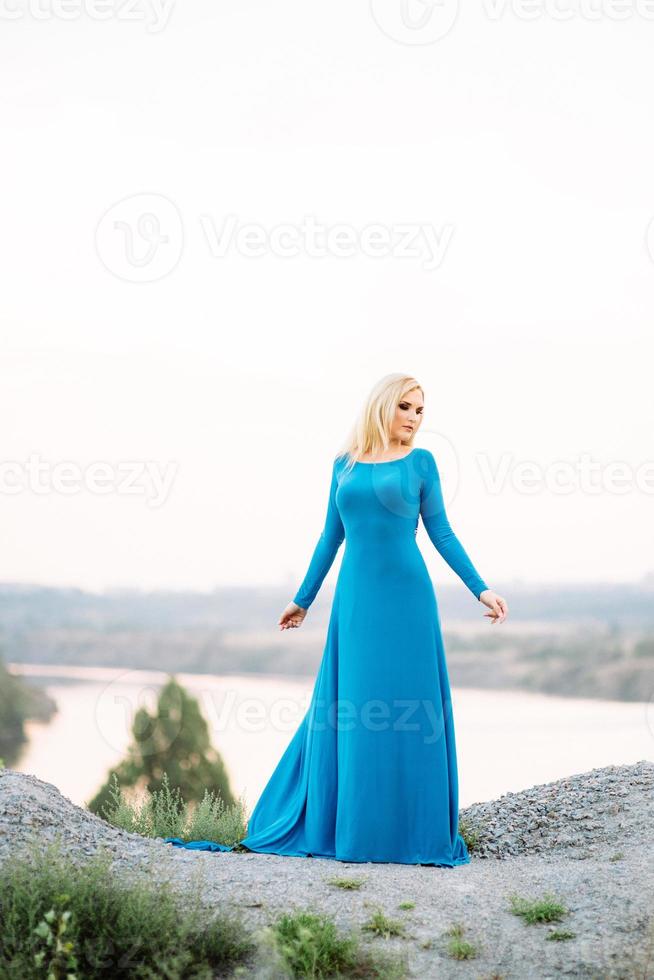 menina loira em um vestido azul com olhos azuis em uma pedreira de granito foto