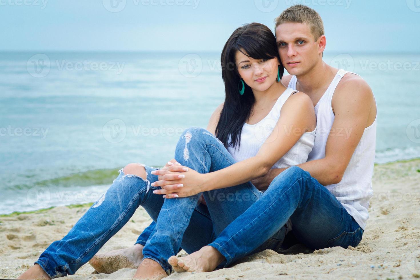 cara e uma garota de jeans e camiseta branca na praia foto
