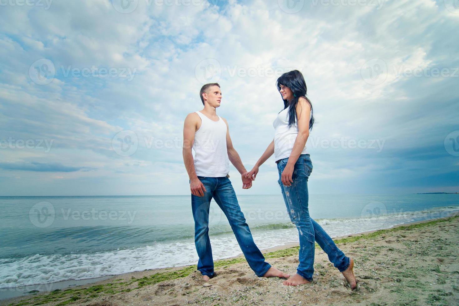 cara e uma garota de jeans e camiseta branca na praia foto