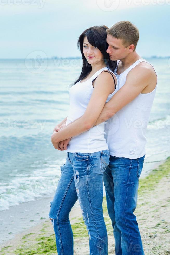 cara e uma garota de jeans e camiseta branca na praia foto