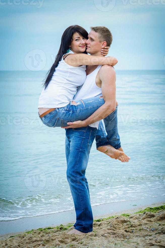 cara e uma garota de jeans e camiseta branca na praia foto