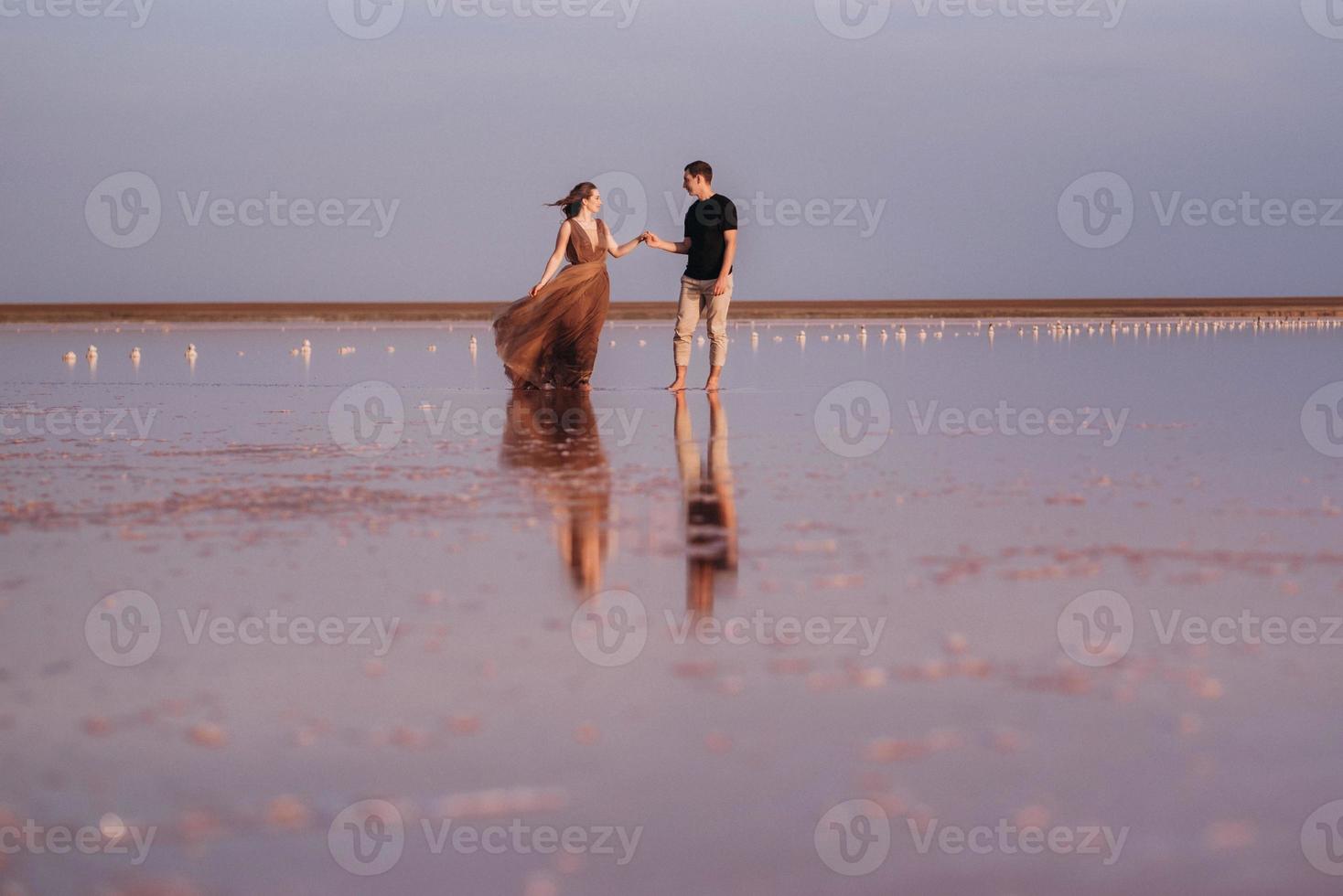 garota e um cara na margem de um lago salgado rosa foto