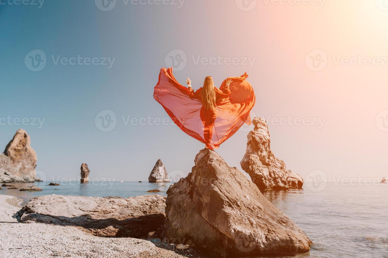 mulher viagem mar. jovem feliz mulher dentro uma grandes vermelho vestir posando em uma de praia perto a mar em fundo do vulcânico rochas, gostar dentro Islândia, partilha viagem aventura viagem foto