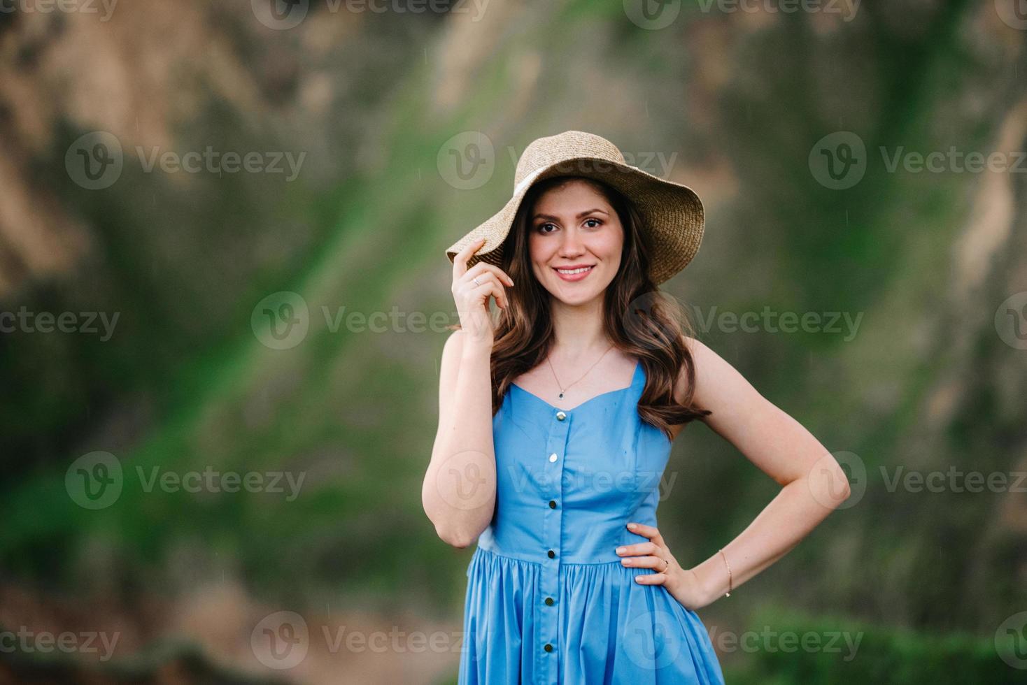 jovem com um chapéu de palha com aba grande nas encostas de uma montanha foto