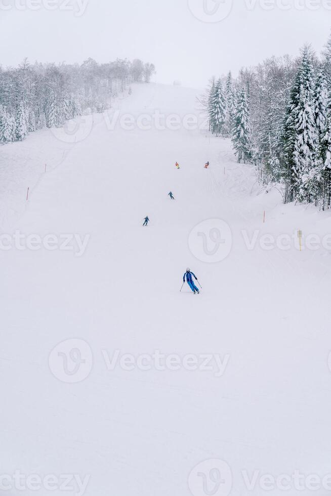 esquiadores esqui em uma Nevado rastrear ao longo uma íngreme declive foto