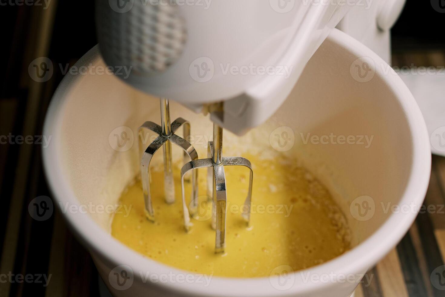 misturador batidas a ovos dentro uma tigela em a mesa. topo Visão foto