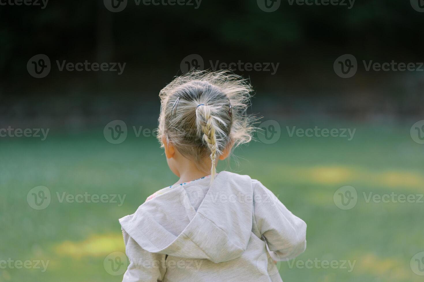 pequeno menina com fluindo cabelo anda em através uma compensação. costas Visão foto