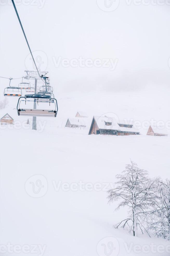 quatro lugares teleférico sobe uma coberto de neve montanha com de madeira cabines foto