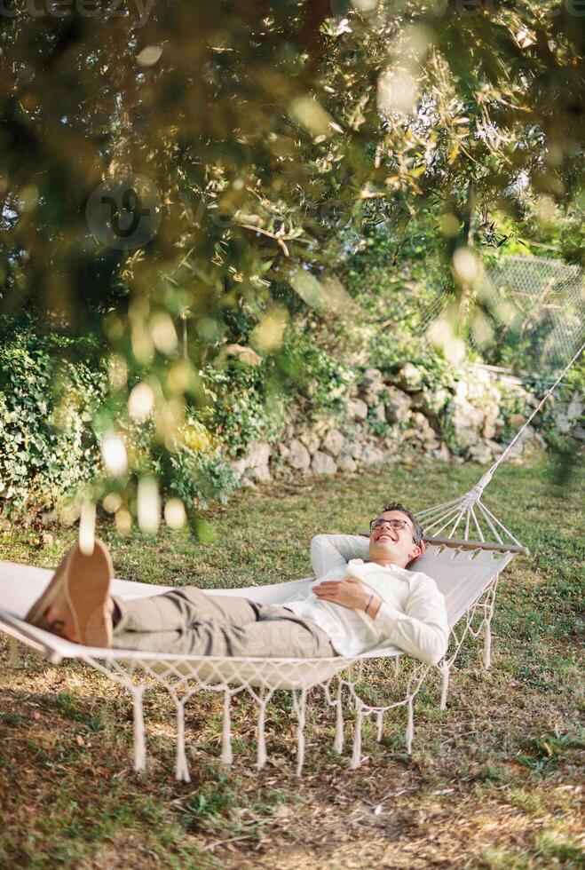 jovem sorridente homem deitado dentro uma maca dentro uma verde jardim foto