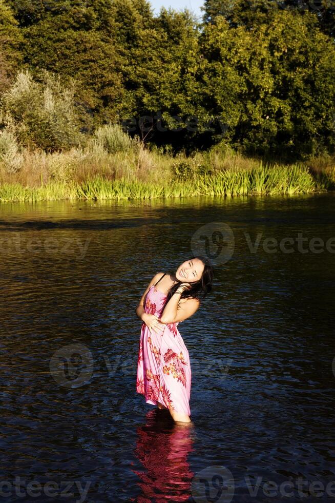 atraente japonês americano mulher em pé dentro rio foto