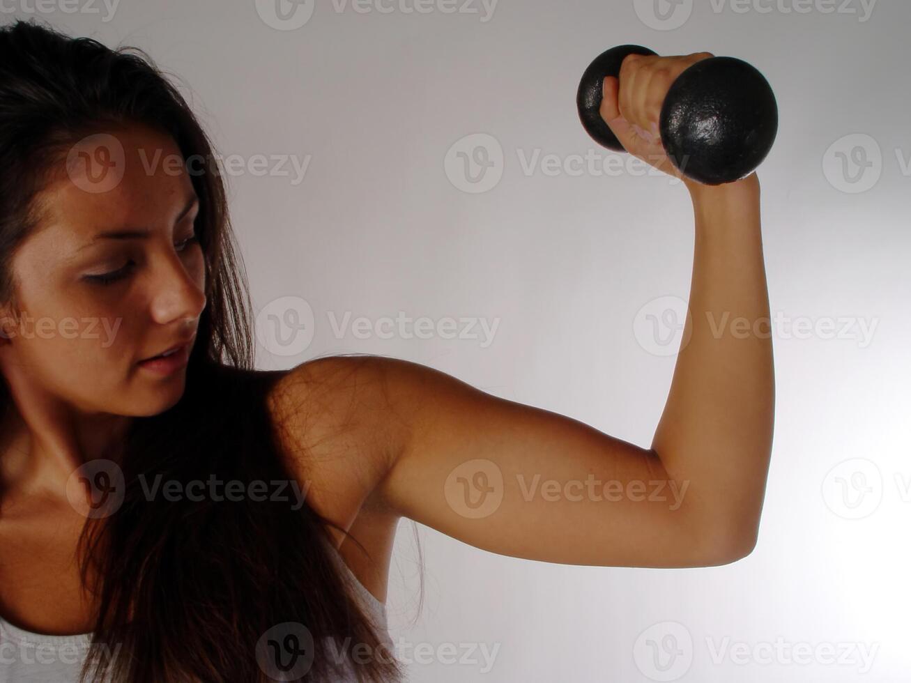 caucasiano mulher braço segurando Preto peso mostrando muscel foto