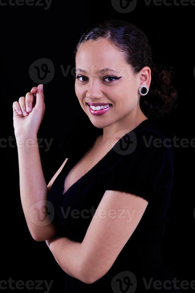 sorridente africano americano mulher dentro Preto vestir em Sombrio fundo foto