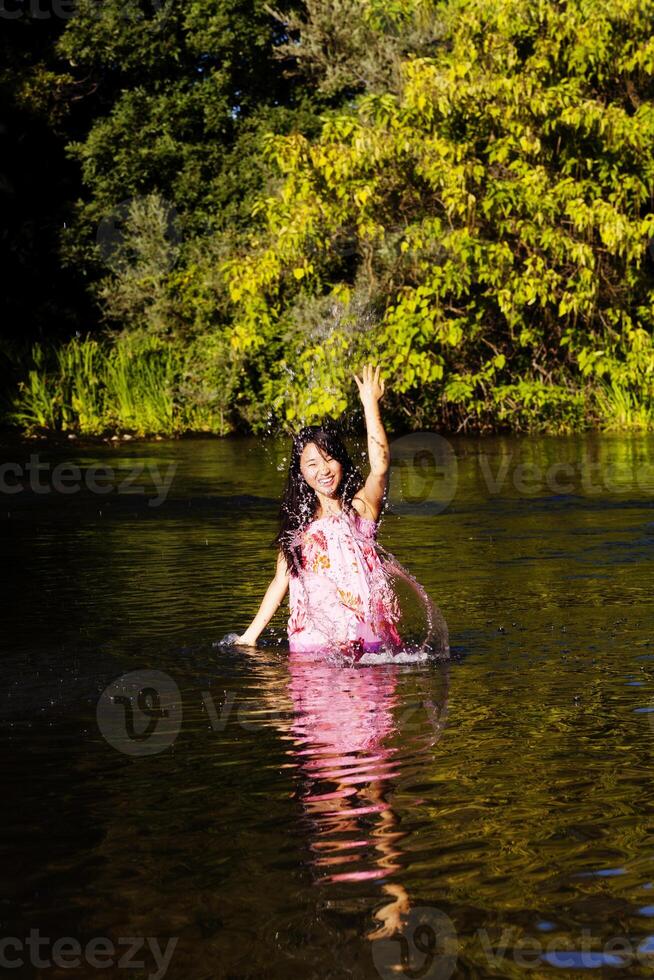 japonês americano mulher dentro rio espirrando água foto