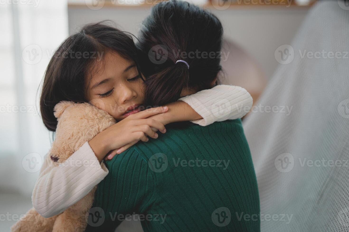 uma mulher é abraçando uma criança e uma Urso de pelúcia Urso foto