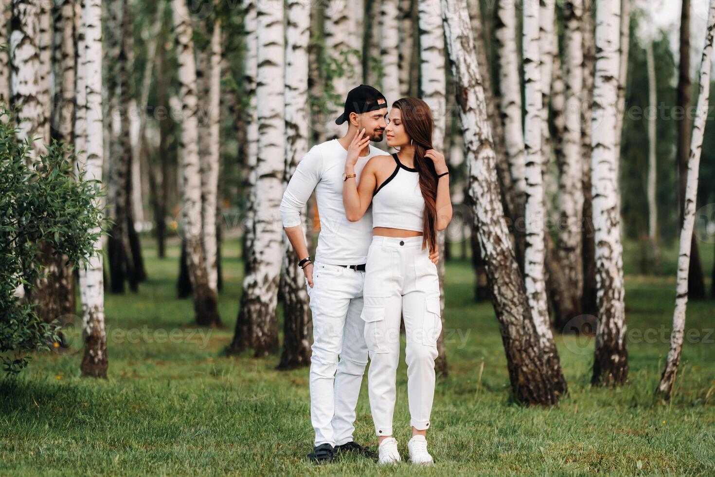 uma jovem lindo casal dentro branco roupas contra a fundo do uma bétula bosque.retrato do pessoas dentro amor dentro uma parque dentro natureza. foto