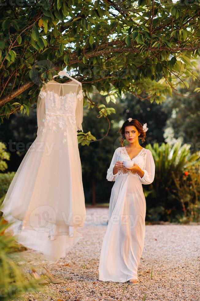 uma lindo noiva carrinhos Próximo para uma Casamento vestir com uma copo do chá dentro uma boudoir equipamento Próximo para uma villa dentro Itália.manhã do a noiva dentro Toscana foto