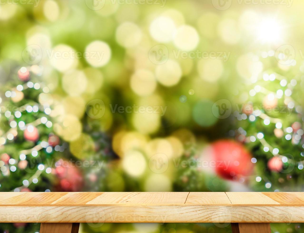 tampo de mesa de madeira marrom com borrão abstrato fundo da árvore de natal com luz bokeh foto