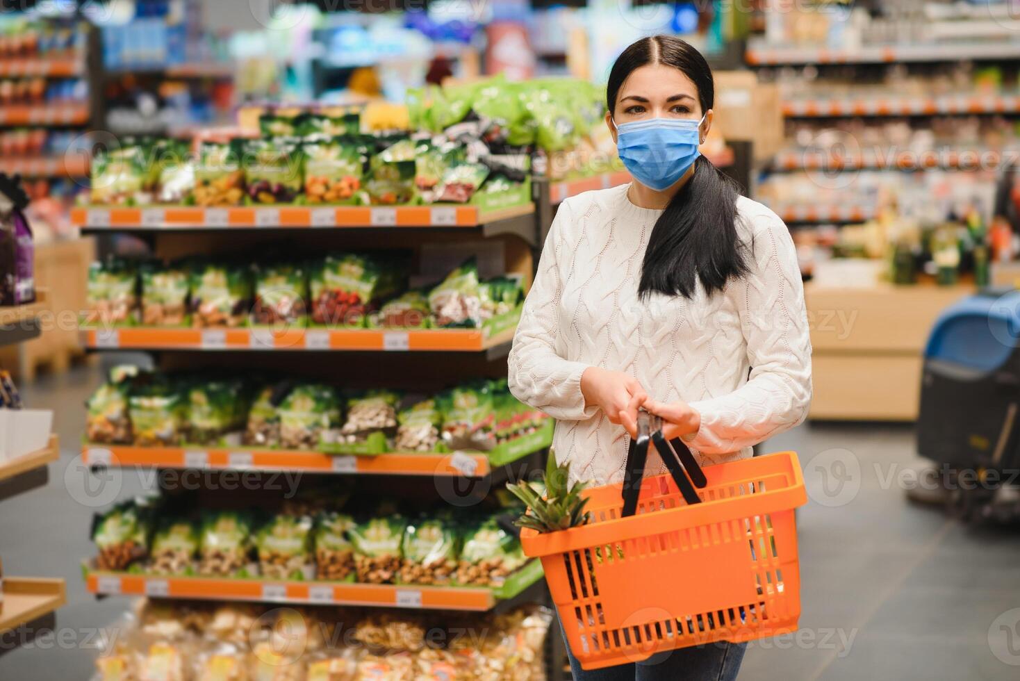 alarmado fêmea desgasta médico mascarar contra coronavírus enquanto mercearia compras dentro supermercado ou loja- saúde, segurança e pandemia conceito - jovem mulher vestindo protetora mascarar e estocagem Comida. foto