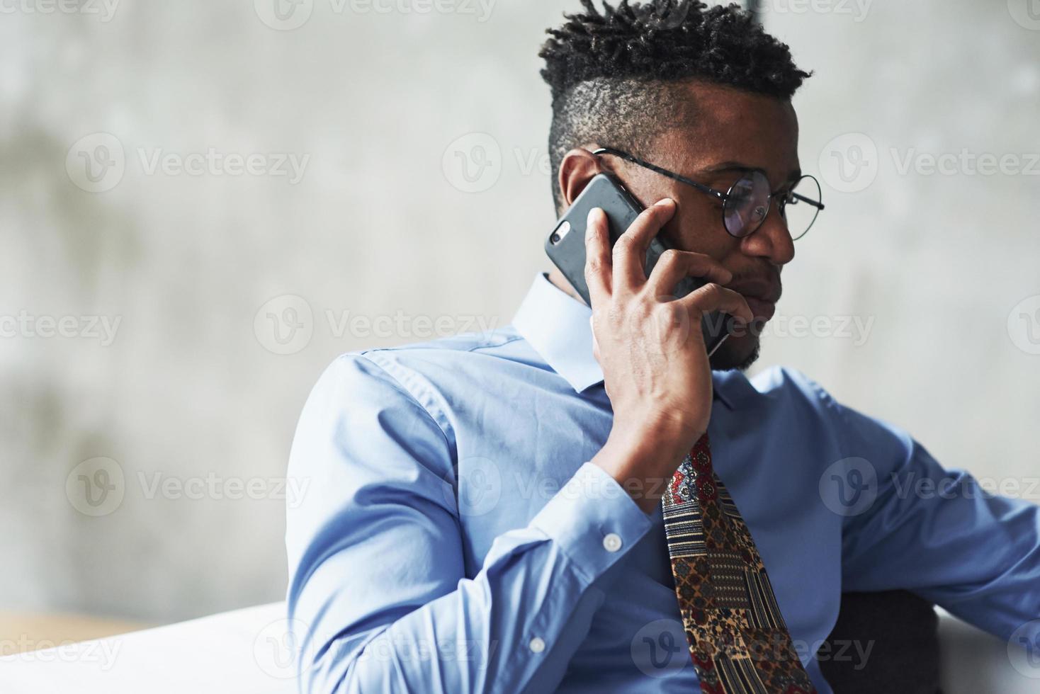 feche a foto do atraente empresário negro elegante em um terno falando de telefone, negociando