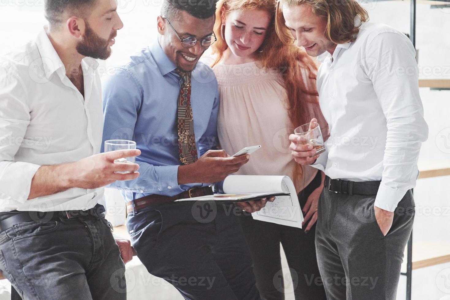 grupo de funcionários de escritório olhando para o telefone do negro conversando foto