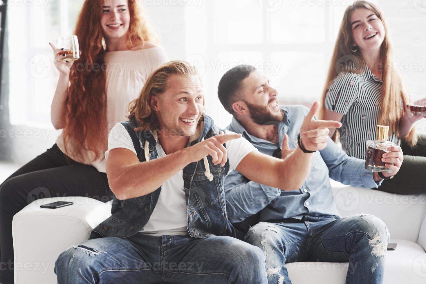 atmosfera sincera. amigos do escritório se divertem sentados e deitados no sofá branco foto