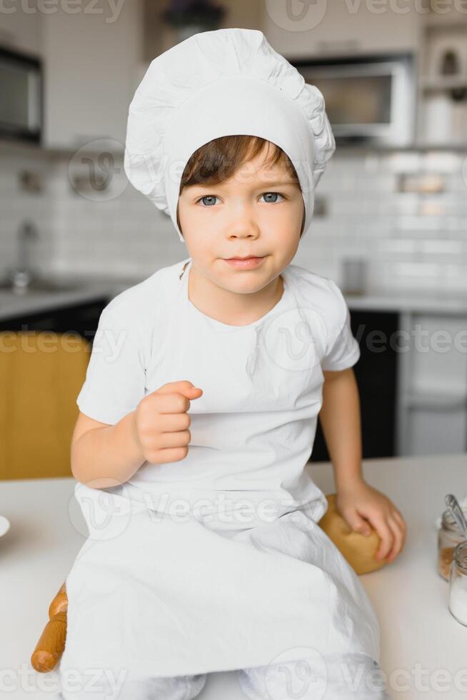 pequeno Garoto dentro cozinha.fofa Garoto desgasta uma chefe de cozinha chapéu e avental. foto