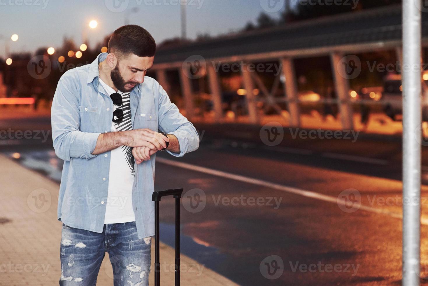 turista de cabelos curtos esperando pelo amigo e verificando quanto tempo falta para a partida foto