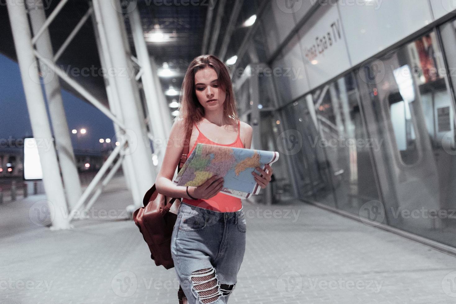 concepção de viajar. garota atraente andando perto do aeroporto e olhando para o mapa nas mãos foto