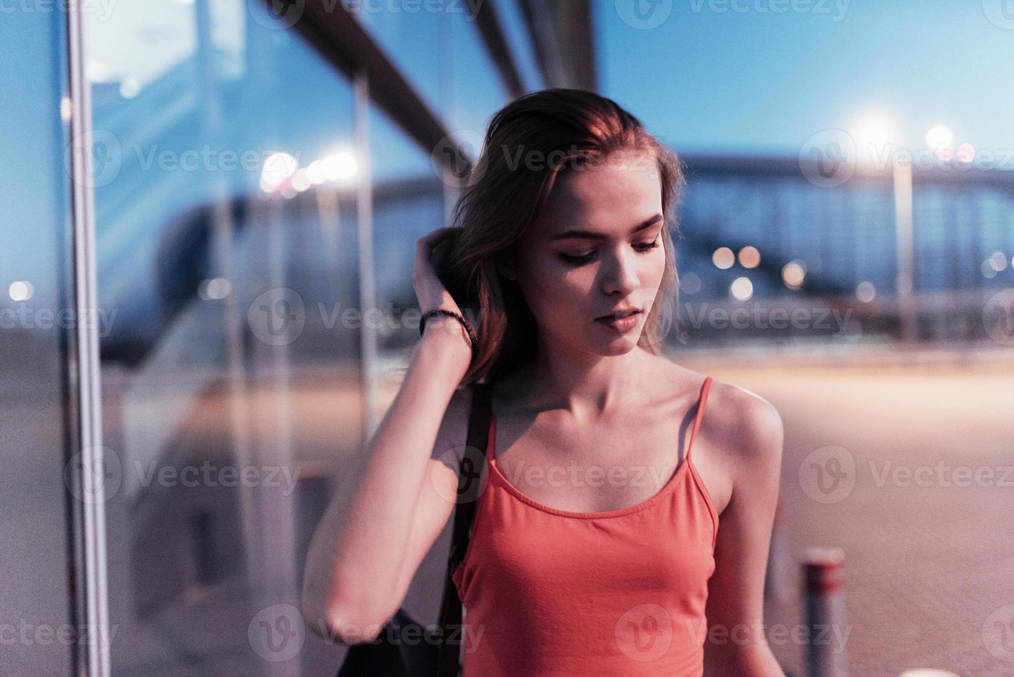 feche o retrato de uma linda jovem caminhando ao entardecer perto dos edifícios foto