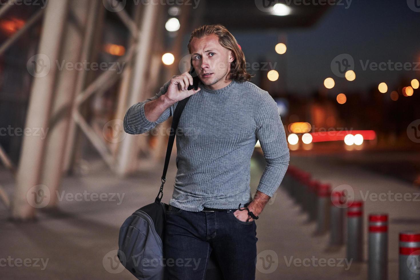 conversando. homem com cabelo comprido e bagagem de viagem esperando o táxi buscá-lo foto