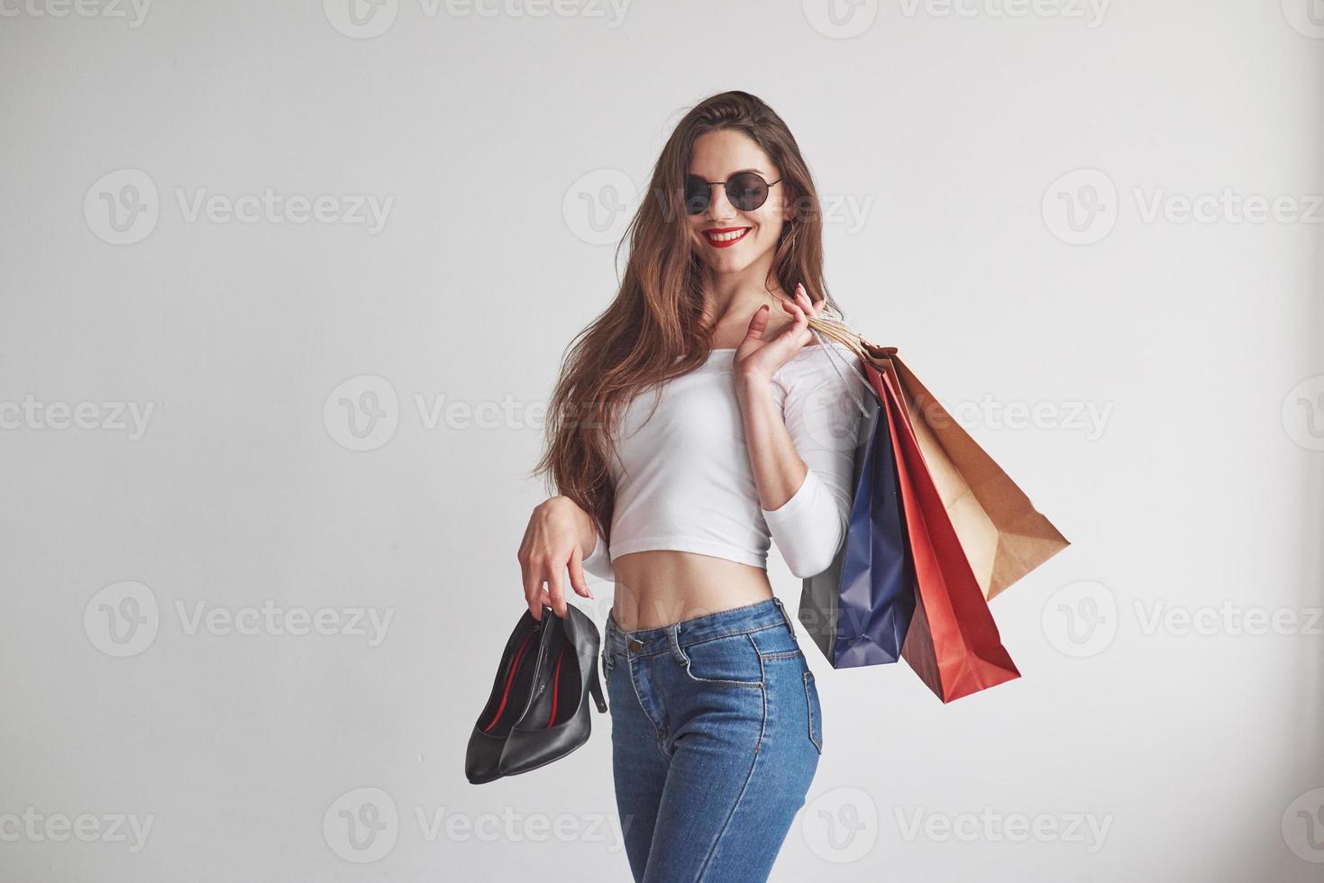 sentindo-se satisfeito com a compra. apenas das compras. elegante jovem segurando os pacotes com roupas e saltos foto