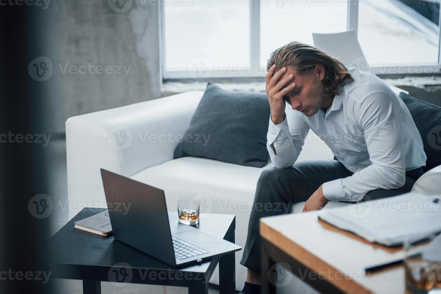 whisky perto do laptop. foto de jovem empresário sentado na carruagem e estressado no trabalho