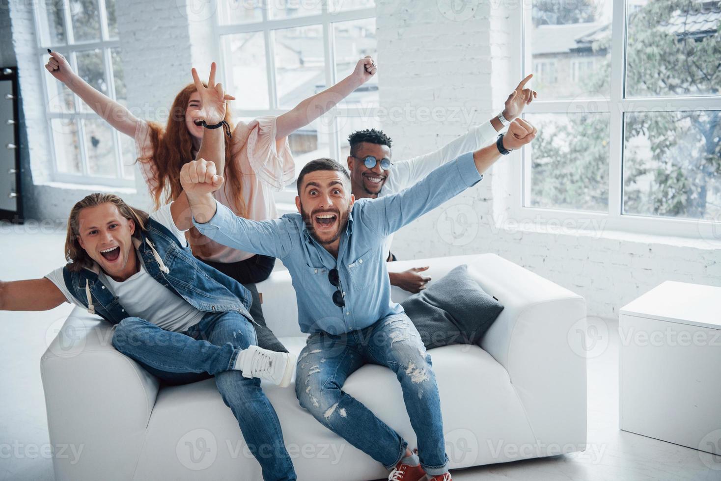 pessoas lindas felizes sentadas no sofá com janelas ao fundo, celebrando seu sucesso foto