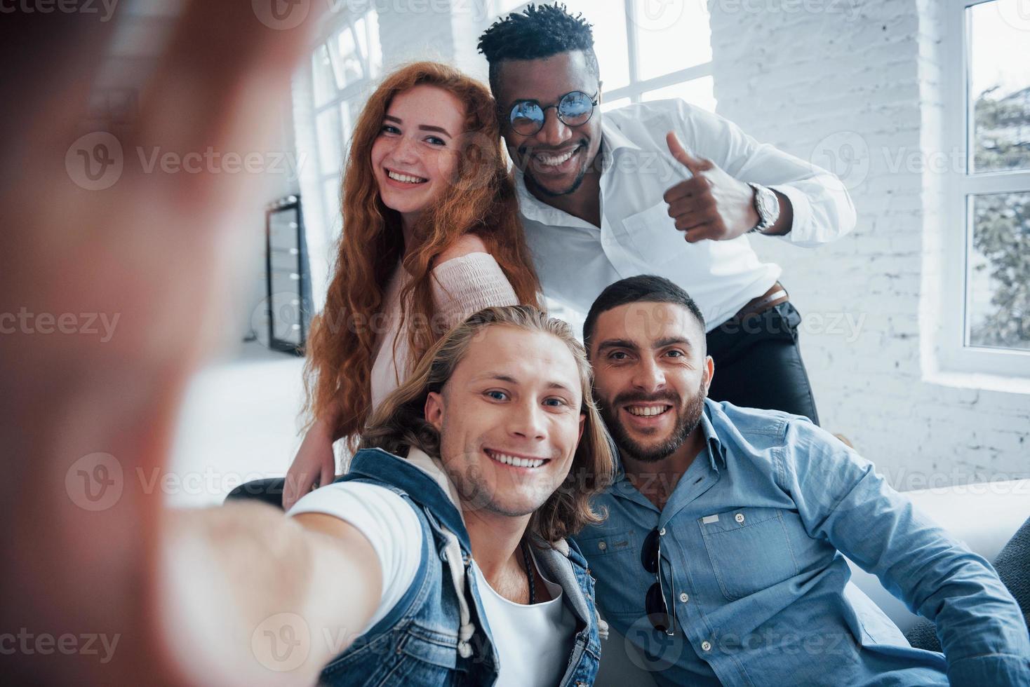 fechar foto. jovens amigos alegres tirando selfies no sofá e no interior branco foto