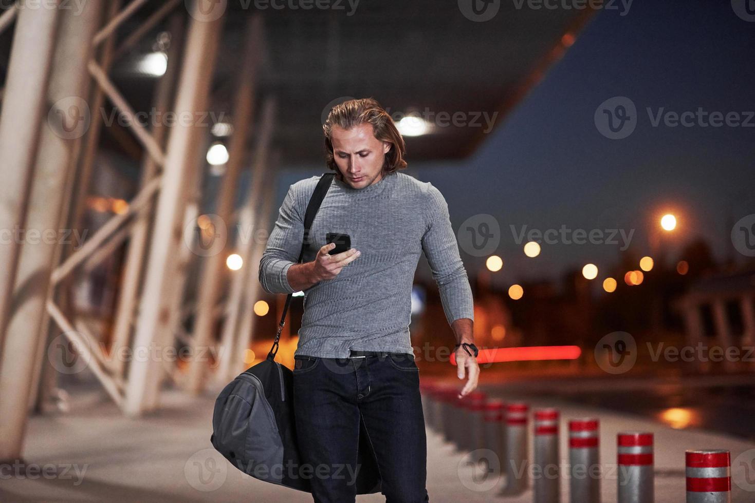 homem com cabelo comprido e bagagem de viagem esperando o táxi buscá-lo foto
